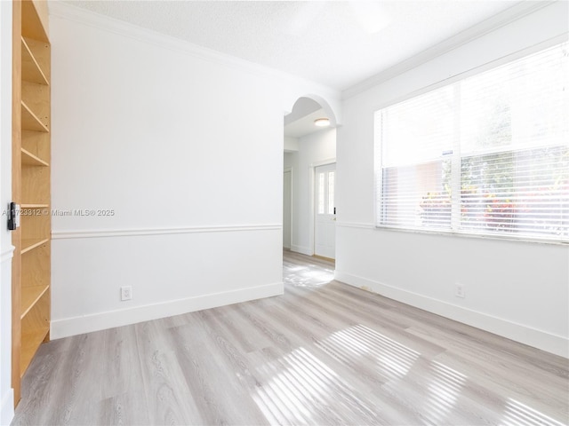 spare room with light wood-type flooring, ornamental molding, and a textured ceiling