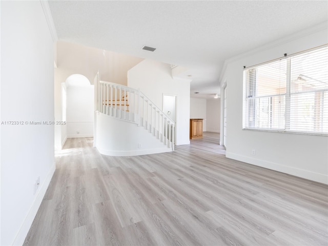 unfurnished living room with light hardwood / wood-style floors, a textured ceiling, and crown molding