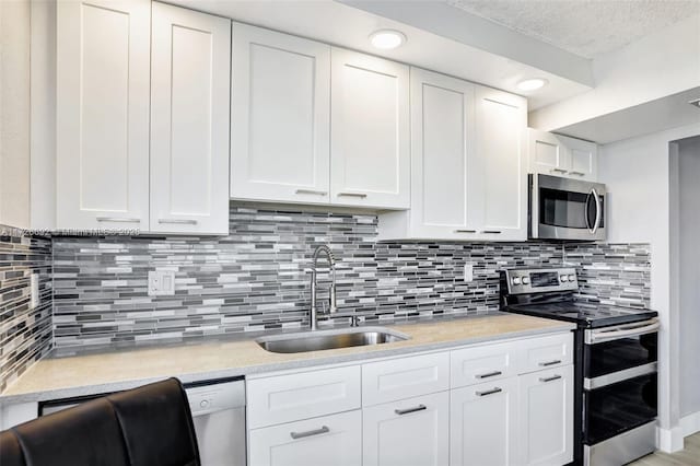 kitchen featuring backsplash, sink, white cabinetry, stainless steel appliances, and light stone counters