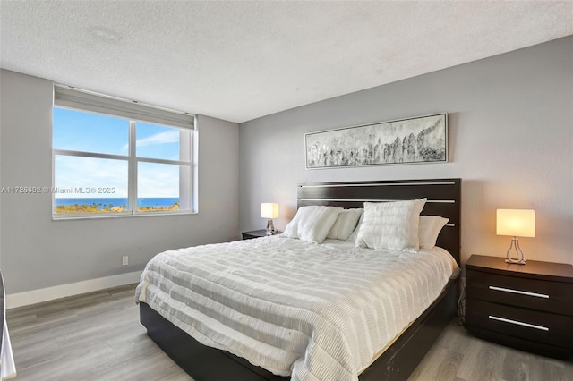 bedroom with light wood-type flooring and a textured ceiling