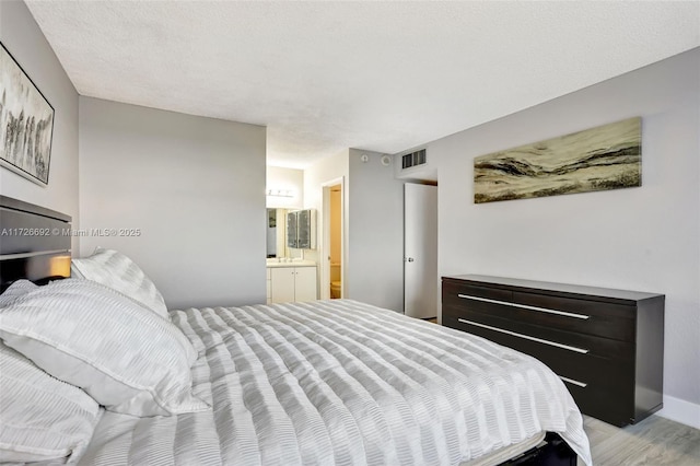 bedroom featuring light hardwood / wood-style floors and connected bathroom