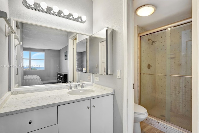 bathroom featuring a shower with shower door, hardwood / wood-style flooring, toilet, and vanity