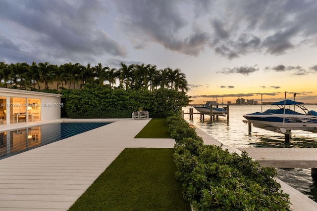 pool at dusk featuring a water view and a boat dock