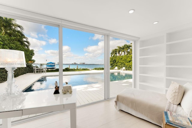 bedroom with access to exterior, a water view, and expansive windows