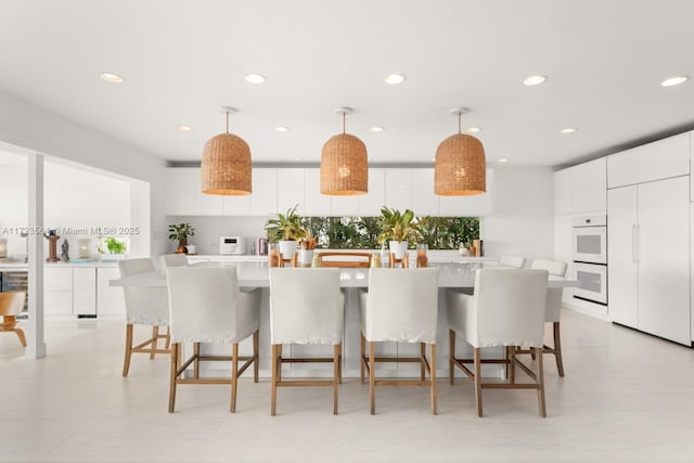 1065 N Shore Dr, Miami Beach, FL 33141 - kitchen with recessed lighting, white cabinets, light countertops, white double oven, and decorative light fixtures