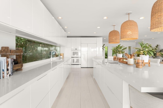 kitchen featuring double oven, white cabinets, paneled refrigerator, and pendant lighting