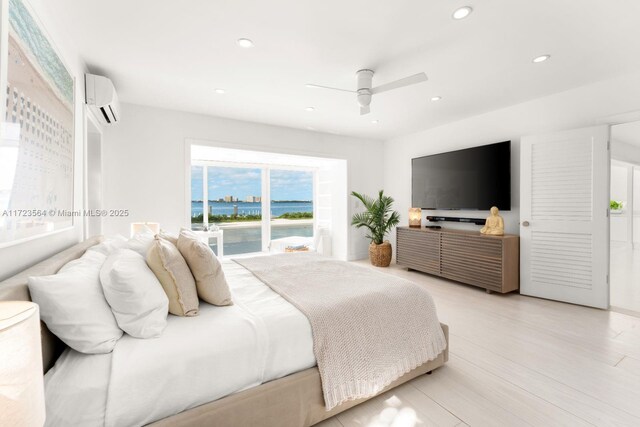 bedroom with ceiling fan, an AC wall unit, and light hardwood / wood-style floors