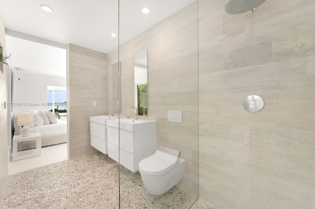 bathroom with tile patterned floors, vanity, a shower, tile walls, and toilet