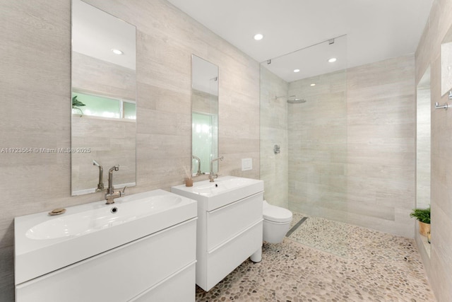 bathroom featuring toilet, vanity, tile walls, and a shower