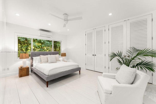 bedroom featuring ceiling fan, a wall unit AC, and two closets