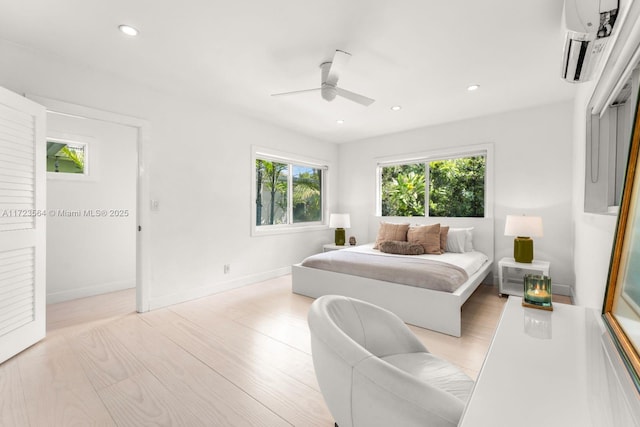 bedroom featuring ceiling fan, light hardwood / wood-style flooring, and a wall mounted AC