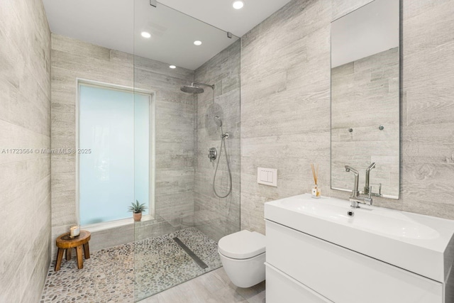 bathroom featuring toilet, vanity, tile walls, and tiled shower