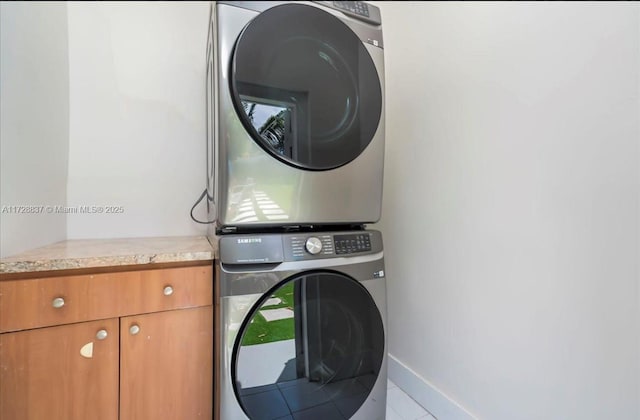 laundry room with cabinets, tile patterned floors, and stacked washer / dryer