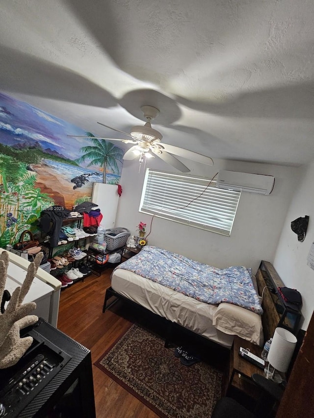 bedroom with a wall unit AC, a textured ceiling, a ceiling fan, and dark wood-style flooring