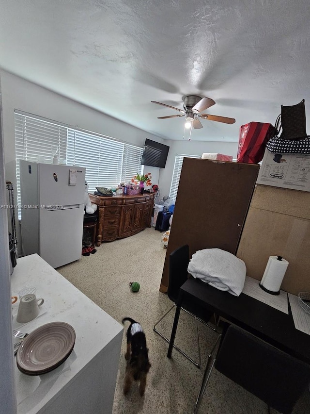 bedroom featuring freestanding refrigerator, ceiling fan, and a textured ceiling