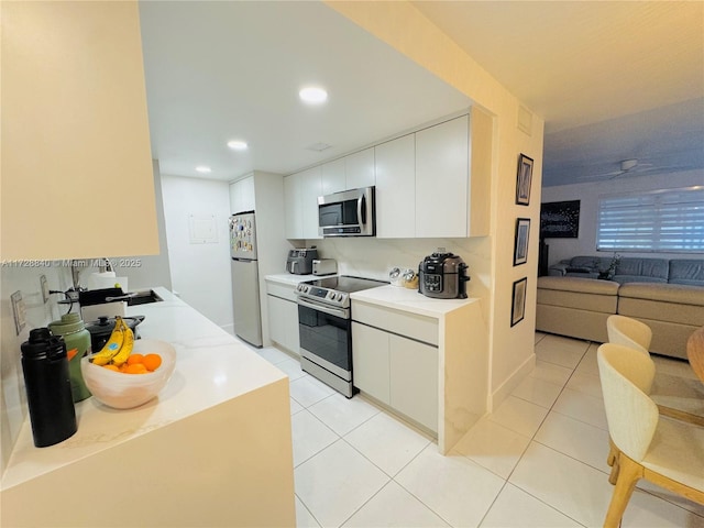 kitchen with sink, light tile patterned flooring, stainless steel appliances, and white cabinetry