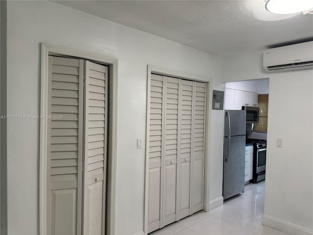 kitchen featuring light tile patterned floors, appliances with stainless steel finishes, a textured ceiling, and a wall unit AC