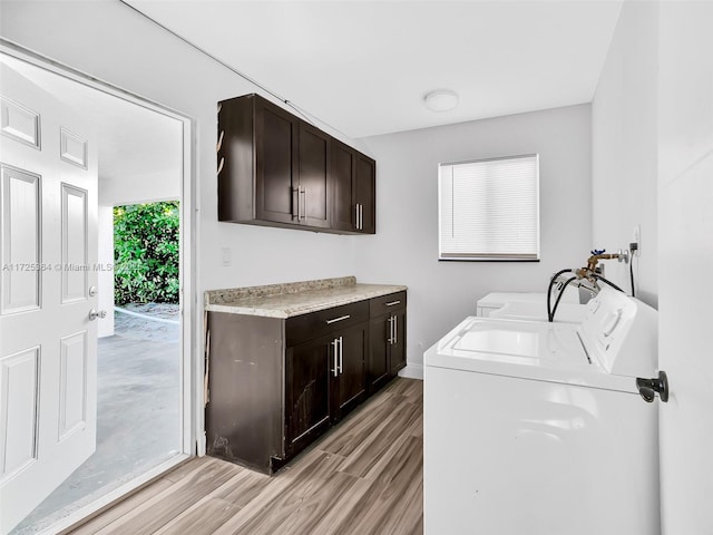 laundry area featuring washer and dryer, cabinets, and light hardwood / wood-style flooring