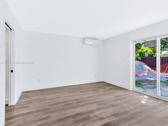 empty room with a wall mounted AC and light hardwood / wood-style flooring