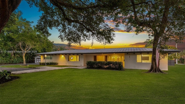 back house at dusk with a lawn