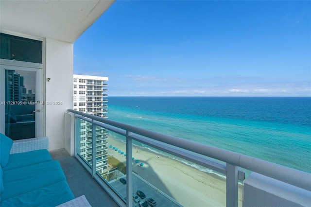 balcony with a water view and a view of the beach