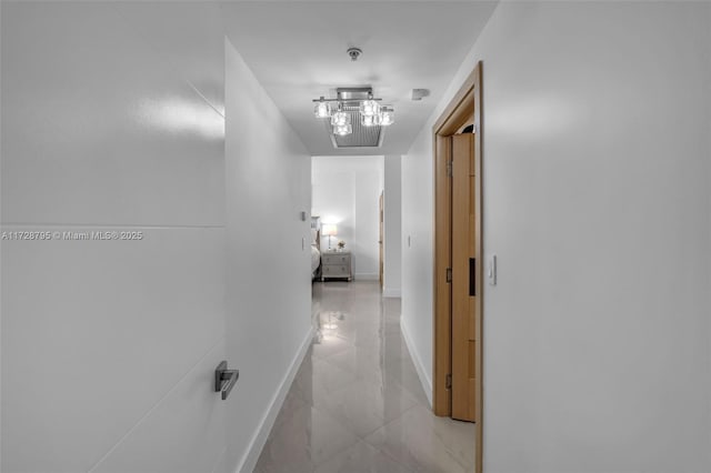 hallway featuring marble finish floor and baseboards