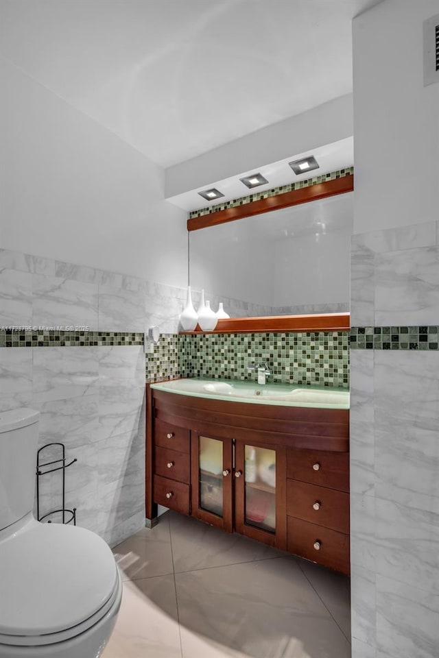 bathroom with tile patterned floors, tile walls, toilet, and vanity