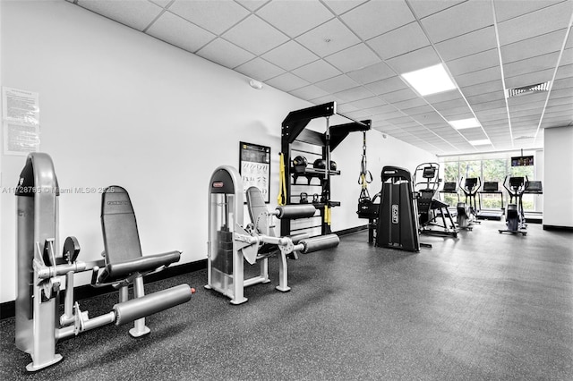 exercise room featuring a drop ceiling and baseboards