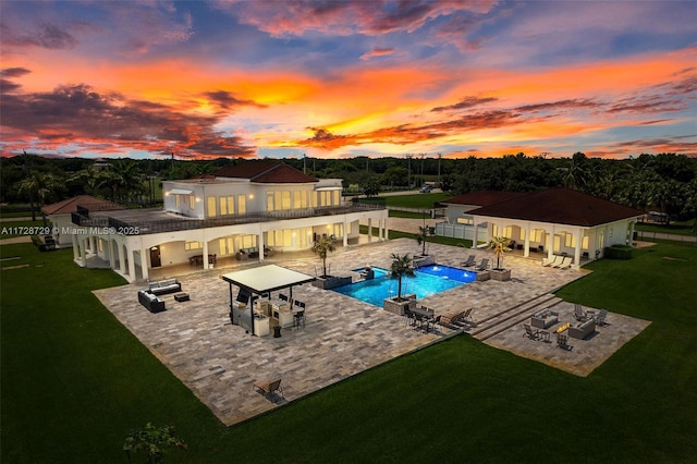 pool at dusk featuring a patio area, a bar, a yard, and an outdoor living space with a fire pit