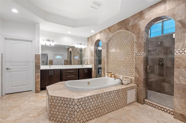 bathroom with plus walk in shower, tile walls, a raised ceiling, and vanity