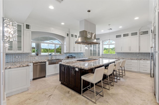 kitchen with light stone countertops, pendant lighting, dishwasher, a kitchen island, and sink