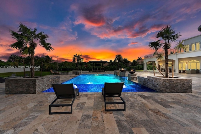 pool at dusk with pool water feature and a patio