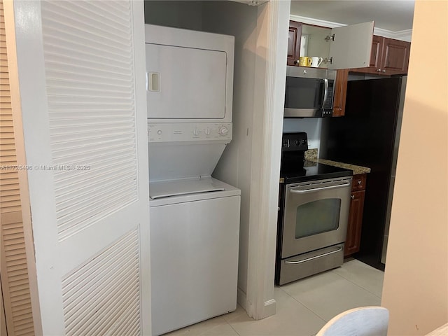 laundry area featuring stacked washer / dryer and light tile patterned flooring