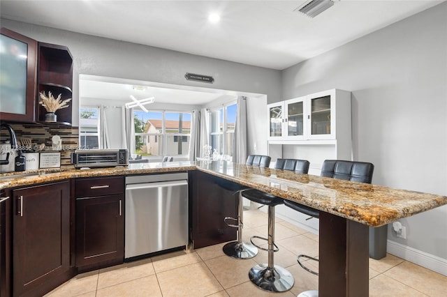 kitchen featuring a breakfast bar, light stone countertops, sink, and dark brown cabinetry