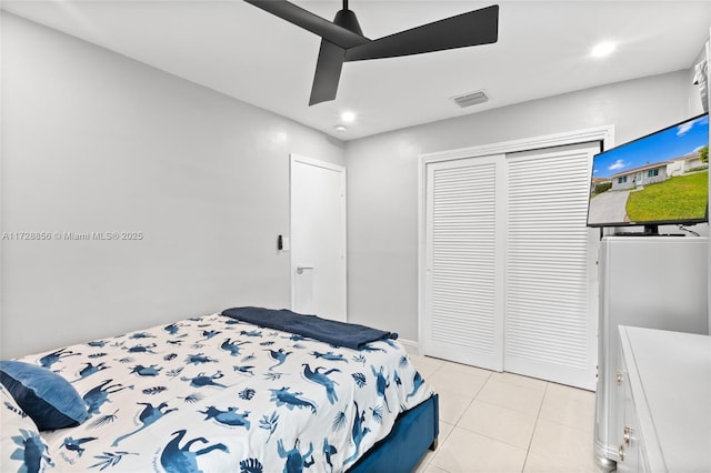 bedroom with ceiling fan, light tile patterned floors, and a closet