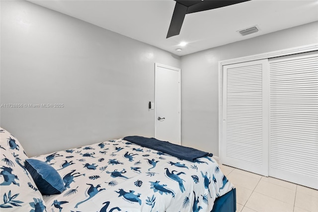 bedroom with a closet, light tile patterned floors, and ceiling fan