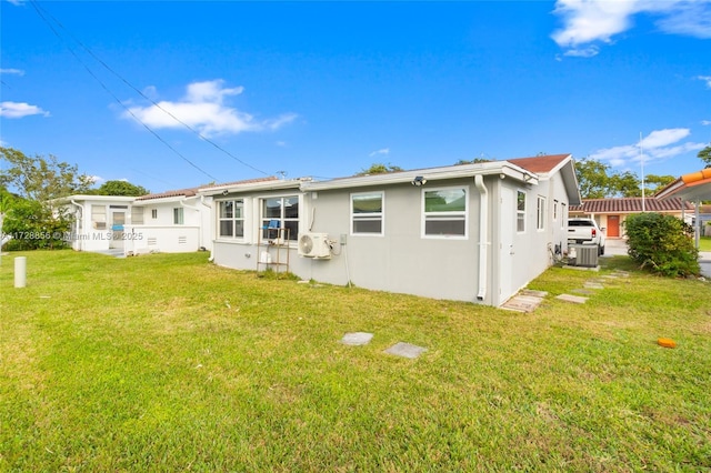 rear view of property featuring cooling unit and a lawn