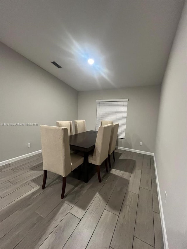 hallway featuring visible vents, baseboards, and wood finished floors