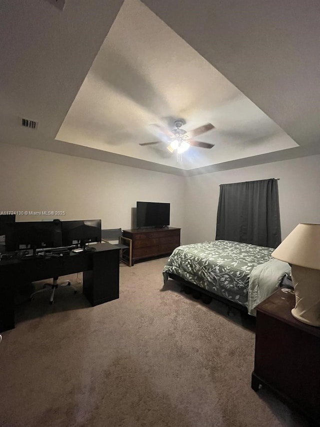 bedroom featuring carpet, ceiling fan, and a tray ceiling