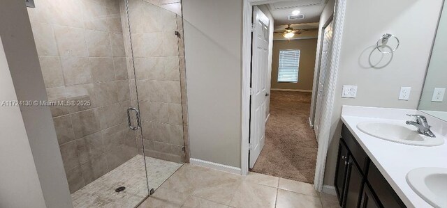 full bath with a shower stall, double vanity, tile patterned floors, and baseboards