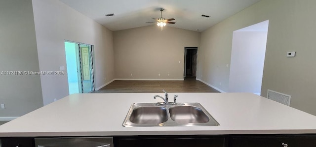 kitchen with a sink, open floor plan, light countertops, and vaulted ceiling