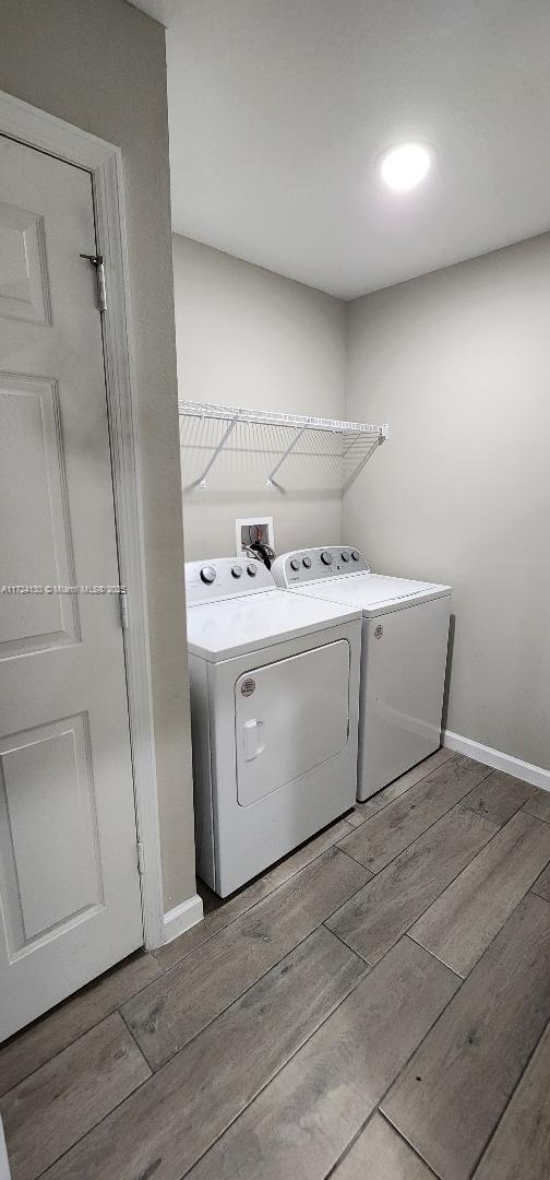 laundry room featuring wood finished floors, washing machine and clothes dryer, and baseboards