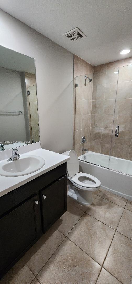 full bathroom with shower / tub combination, vanity, tile patterned flooring, toilet, and a textured ceiling