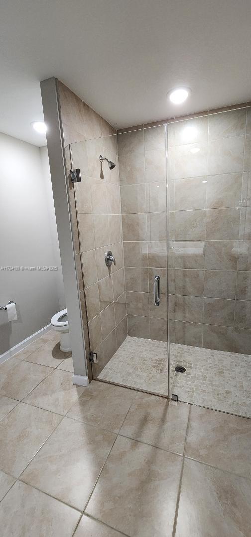 full bath featuring toilet, a stall shower, tile patterned flooring, recessed lighting, and baseboards