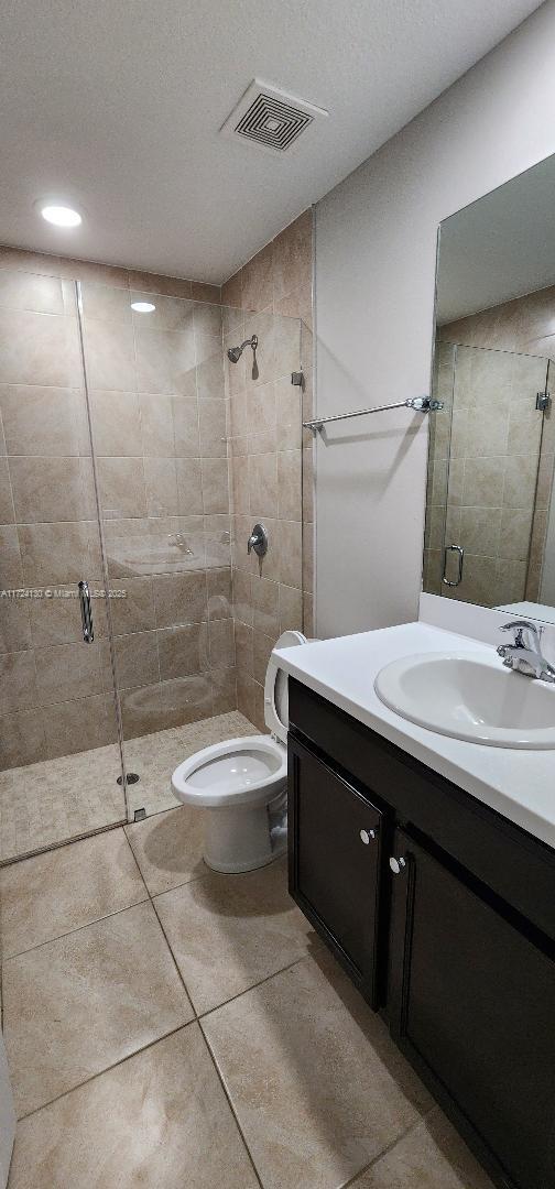 unfurnished bedroom featuring a closet, baseboards, ensuite bath, ceiling fan, and light colored carpet