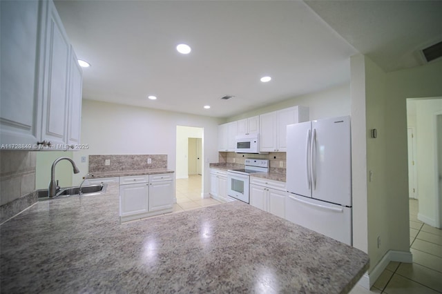 kitchen with white cabinetry, kitchen peninsula, white appliances, light tile patterned flooring, and sink