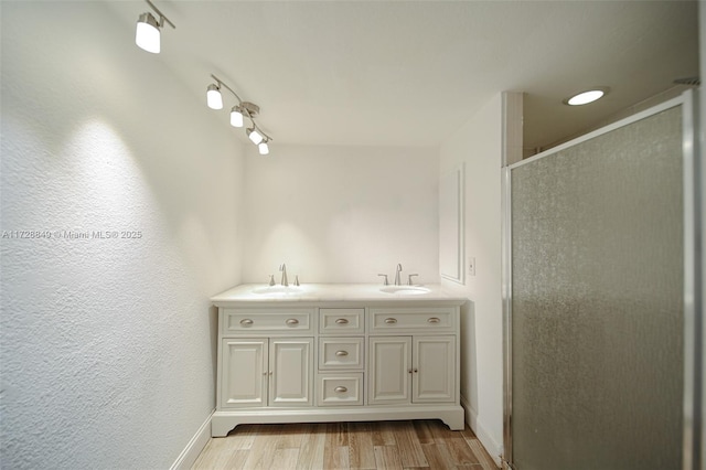 bathroom with a shower with shower door, hardwood / wood-style flooring, and vanity