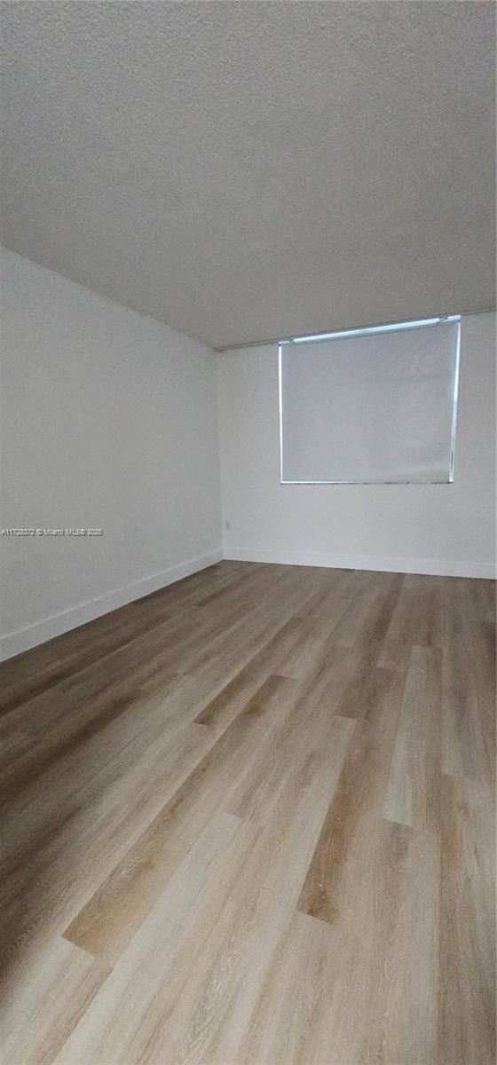 empty room featuring a textured ceiling and light wood-type flooring