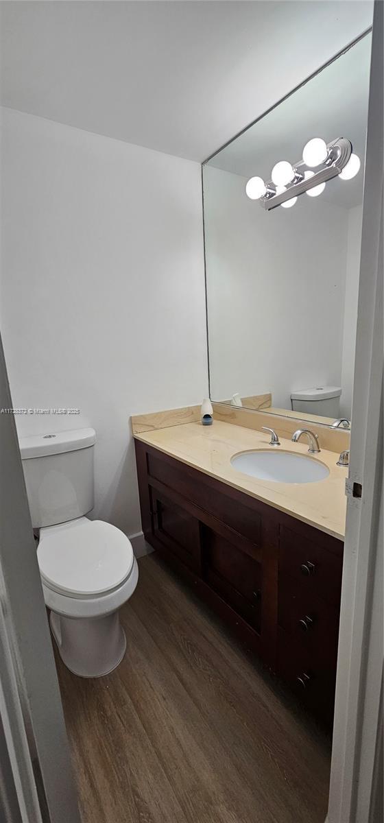 bathroom with hardwood / wood-style flooring, vanity, and toilet