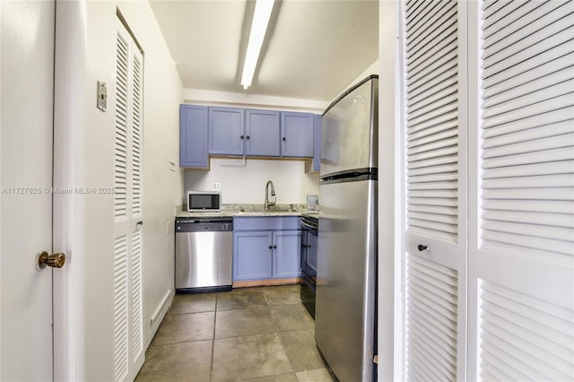 kitchen with dark tile patterned flooring, sink, light stone counters, and stainless steel appliances